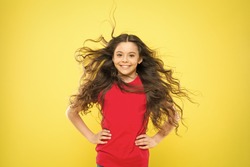 Feeling good fabulous hair. Adorable small girl smiling with long brunette hair. Happy child with flowing hair on yellow background. Little kid with cute smile and wavy textured hair.