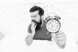 Time to wake up. Healthy habits. Beginning of awesome day. Wake up early every morning. Health benefits of rising early. Waking up early gives more time. Hipster bearded man in bed with alarm clock