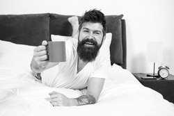 Drink with relish. Happy hipster offer hot cup. Pleasure of coffee. Bearded man give cup of coffee. Enjoying cup of pleasure. Pleasure and joy. Pure pleasure. Enjoy yourself. Good morning
