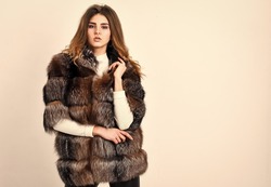 Winter elite luxury clothes. Female brown fur coat. Fur store model posing in soft fluffy warm coat. Pretty fashionista. Fur fashion concept. Woman makeup and hairstyle posing mink or sable fur coat