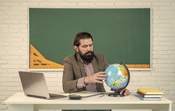 find a place. prepare for exam. college lecturer on geography lesson. back to school. informal education. serious mature teacher looking at globe. bearded man geographer work in classroom with map