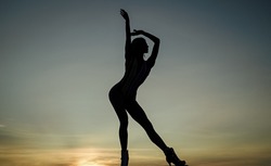 Free dance of woman ballet dancer silhouetted in dusk on evening sky, freedom