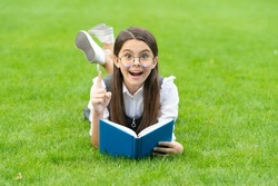 Happy teenage girl with book got idea keeping finger raised lying on grass, idea. Genius idea