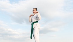 karate concept. teen girl practicing karate. smiling girl karate fighter on sky background