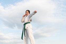 karate concept. teen girl practicing karate. cheerful girl karate fighter on sky background