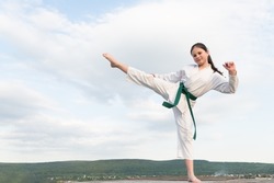 karate concept. teen girl practicing karate. girl karate fighter on sky background. copy space