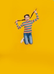 childhood studio shot of jumping teen braided girl. teen braided girl isolated on yellow background.