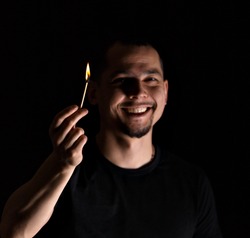Caucasian man holding burning match stick and smiling on the background