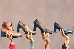 Hands holding different women shoes and boots. Concept of selection, purchase and repair of shoes