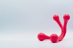 Unusual red object on a light background with place for text, bokeh effect, body massager made of red plastic of unusual shape, unusual background 
