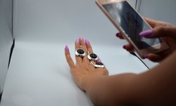A girl photographs jewelry in a lightbox, creating a photograph in a lightbox, filming process, photographing on a white background, silver jewelry earrings and a earrings and a ring