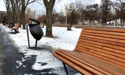Urban bench in the park in winter, urban urn on the Avenue in the park, a trash can from black plastic in urban urn, winter in the city, wooden bench 