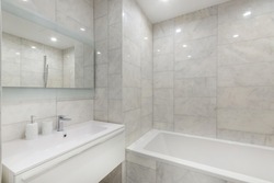 Simple bathroom interior with bathtub,  sink, and marble walls