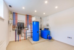 Autonomous boiler room with blue tanks and multicolored pipes of the heating system.