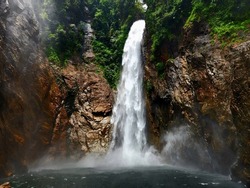 Waterfall Malaysia with strong water current surrounded by lush green jungle