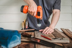 Man drilling wood with battery power Drill on the table in renovation work at home