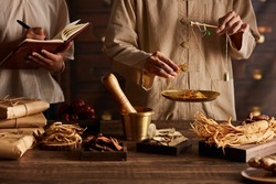 A moment of apocathery measuring ingredient in gold scale with chinese traditional medicine in wooden table 