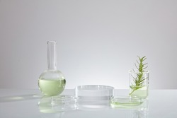 Front view of transparent podium with laboratory equipment and green leaf in white background science content