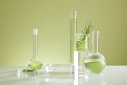 Photoshoot over the course of experiment on green leaf , the research on chemistry lab , fluid in beaker and laboratory equipment and transparent podium with blank space for product