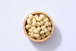 Top view, flat lay of Lotus (Nelumbo nucifera) seeds placed in wooden bowl on white background. Copy space. Very healthy ingredients.