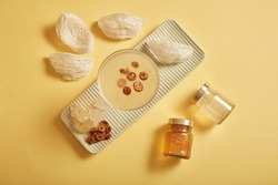 Mockup scene for product with glass bottles without label, bowl soup, raw bird’s nest, jujube and rock sugar on yellow background. Bird's nest is an expensive culinary ingredient