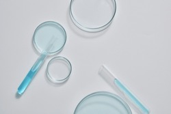 Minimal scene with some glass petri dishes decorated with test tubes filled with blue fluid on white background. Empty area for product display, copy space