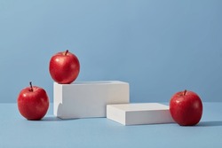 White podium in rectangle-shaped decorated with apples over a blue background. Apple (Malus domestica) helps to inhibit the increase of sebum secretion