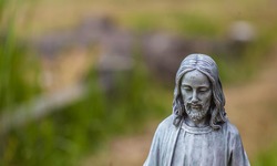A stone statue of jesus against a blurry background