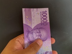 
Someone hand holding Indonesian money, Rupiah,  10.000 bill over dark background