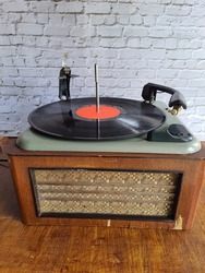 Vintage turntable with retro vinyl record. Antique wooden turntable with a vinyl record, retro style, on an antique wooden table, front view.