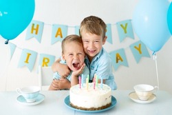 cute kids kids boys celebrate their birthday with blue balloons and a sweet birthday cake on a white background. Happy birthday, happy kids