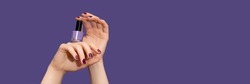 Female hands with purple nail design. Glitter purple nail polish manicure. Female hands hold purple nail polish on purple background. Copy space. Banner ad template. Advertising banner.