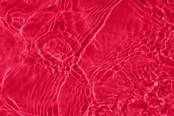 Defocus blurred transparent red colored clear calm water surface texture with splash, bubble. Shining red water ripple background. Surface of water in swimming pool. Red bubble water shining.