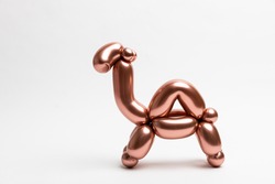 A cute little camel made from a 260 magic balloon with a Reflex Rosegold color on a white background.