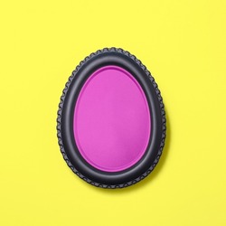 Egg shape made of car tire on a bright yellow background  with a pink fill. Minimal easter concept.  Flat lay.
