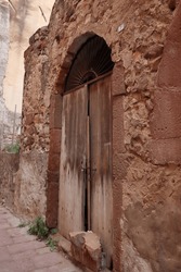 Old wooden door of an entrance of a ruined stone house. upright image.