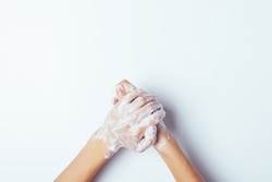 Hygiene to protect human health from viruses, hand washing with soap process on white background, top view.