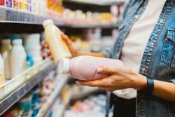 Close-up of bottled dairy products in female hands at grocery store