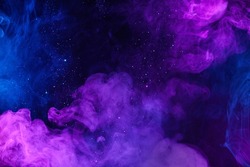 Shiny glitter particles in clouds of pink and blue colorful smoke abstract background