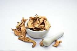 organic dried ginger in white ceramic mortar with pestle 