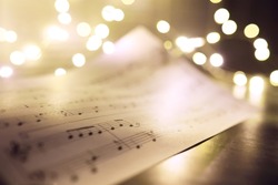 Old sheet with Christmas music notes as background, bokeh effect