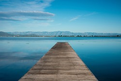 Seascape with wooden breakwater. Morning of blue sky and sea. Symmetrical image.