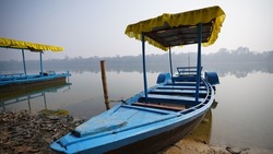 Blue wooden boat with yellow canopy on the water in a foggy morning