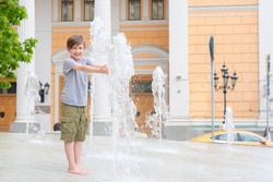 happy child stands in a fountain in the historical center of europe. a boy plays in a dry fountain in summer.