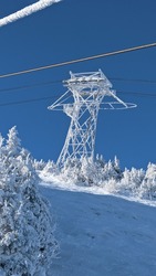 Frozen chairlift tower with frozen cable in view above