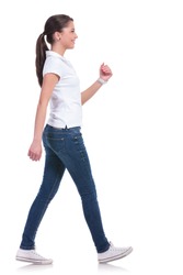 side view of a casual young woman walking away from the camera and smiling. isolated on white background
