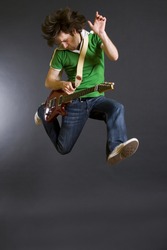 passionate guitarist jumps in the air over dark background