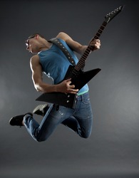 passionate guitarist jumps in the air over black
