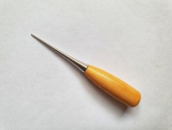 Leather craft awl with wood handle. A leather awl is a tool with sharp metal point used for marking, piercing, punching, or sewing leather and leather goods.