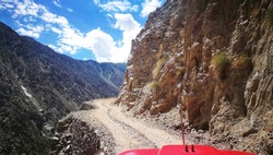 A Jeep Ride on the dangerous and serpentine road in a rock mountain to Fairy Meadows, Nanga Parbat, Karakorum, Northern Area Of Pakistan with background of blue sky and dramatic cloud